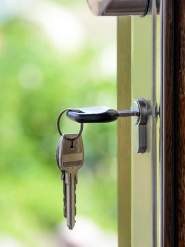 Key inserted in door lock against a blurred green background, symbolizing security and real estate.